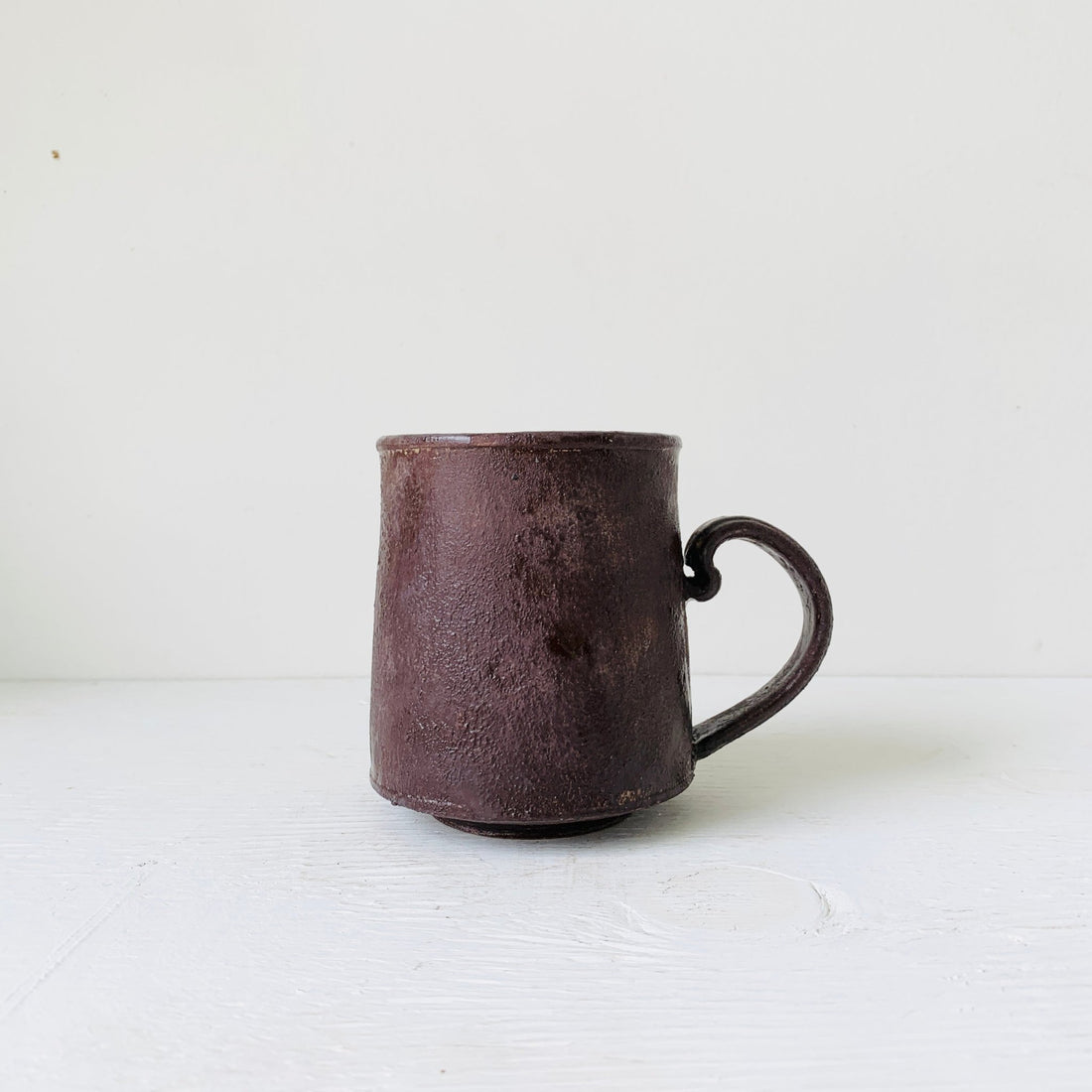 Handmade ceramic mug with a modern handle and organic color palette, ideal for coffee or tea.